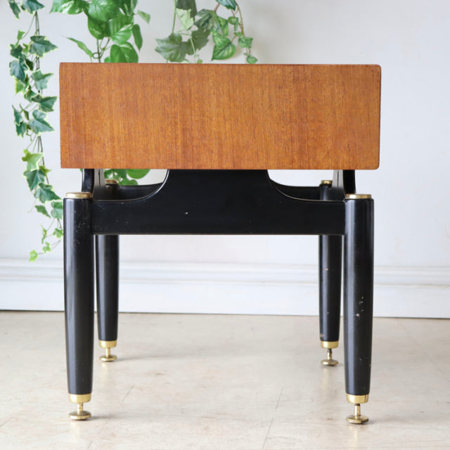 Vintage British mid-century teak bedside cabinet with black tapered legs and brass feet.