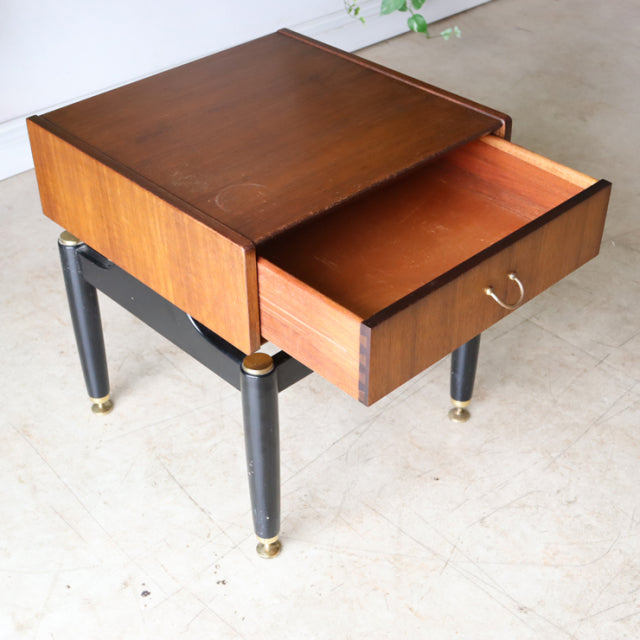 Vintage British G-Plan teak bedside cabinet with black tapered legs and brass-capped feet, mid-century modern style, open.
