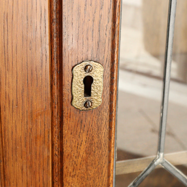 Close-up of teak wood grain on vintage Jaycee British mid-century cabinet door with brass keyhole plate and metal frame.