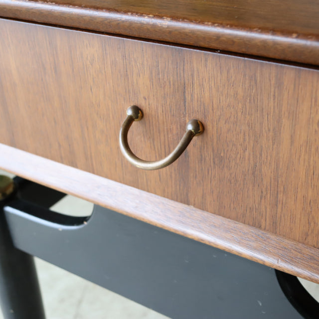 Vintage British mid-century teak bedside cabinet drawer with brass handle and black lacquered base.