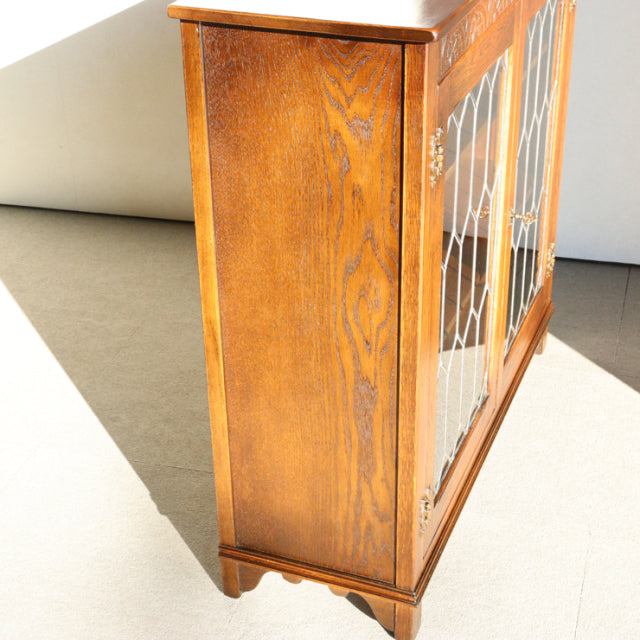 Vintage teak wooden cabinet by Jaycee, British mid-century design with detailed wood grain, slender legs, and glass-paneled.