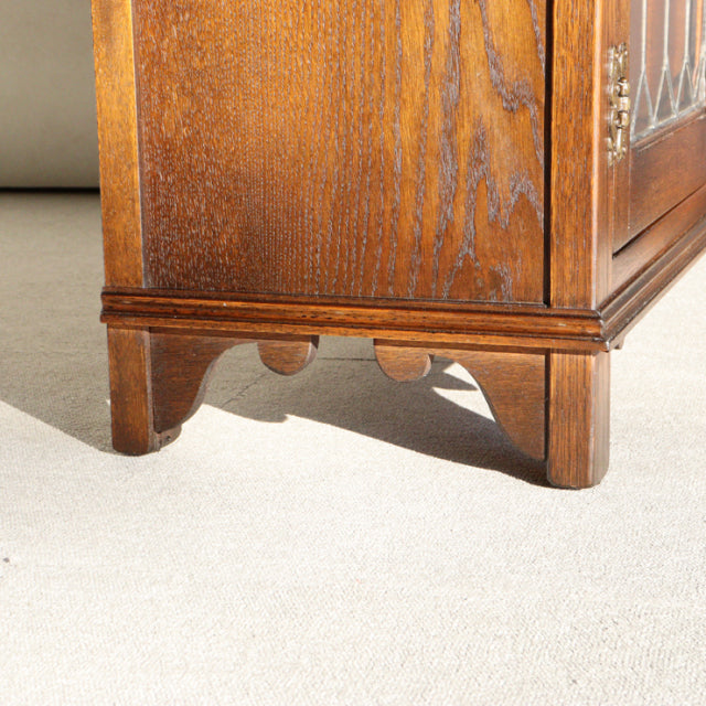 Mid-century vintage teak cabinet corner with detailed wood grain and carved British-style bracket legs.
