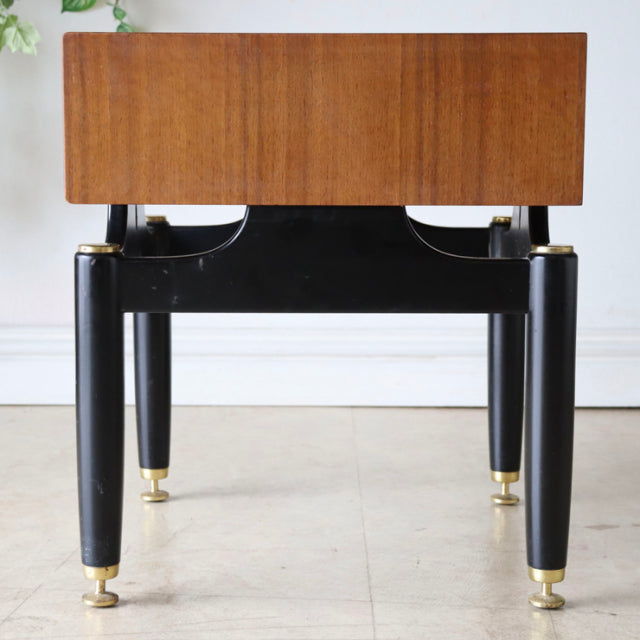 Vintage British mid-century teak bedside cabinet with black lacquered legs and gold brass leg caps.