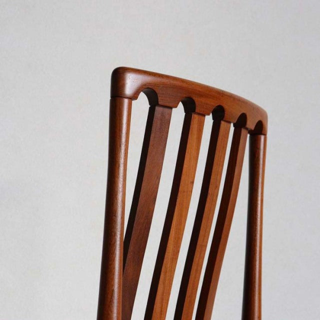 Mid-century British Meredew dining chair in teak with curved top rail and vertical slat backrest showing rich wood grain.