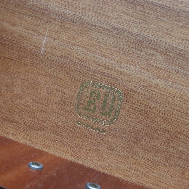 Close-up of vintage British G-PLAN teak wood showing clear wood grain and green logo stamp on mid-century furniture piece.