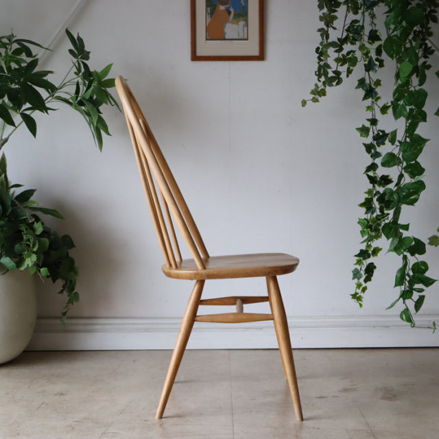 British mid-century Ercol Quaker chair in natural teak with slender spindle back and tapered legs showing smooth wood grain.