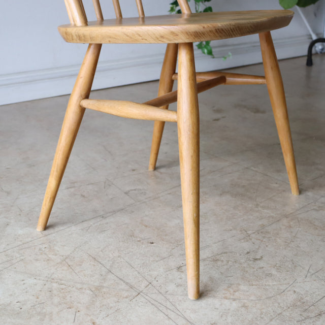 Mid-century British Ercol Quaker dining chair in natural teak with smooth wood grain and angled legs.