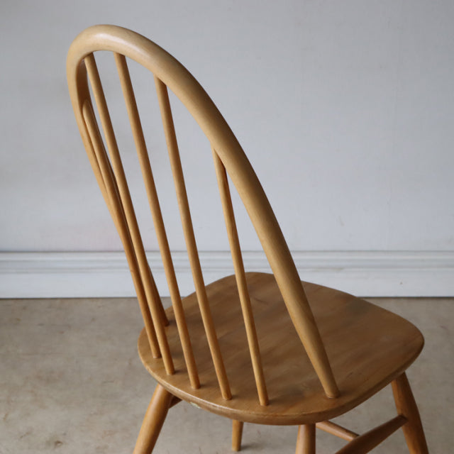 Vintage British Ercol Quaker chair in natural teak with curved spindle back and tapered legs, mid-century Danish design.