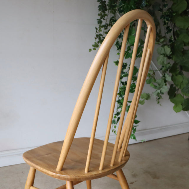 Vintage ERCOL Quaker chair in natural teak with gracefully curved spindle back and tapered legs, showcasing mid-century.