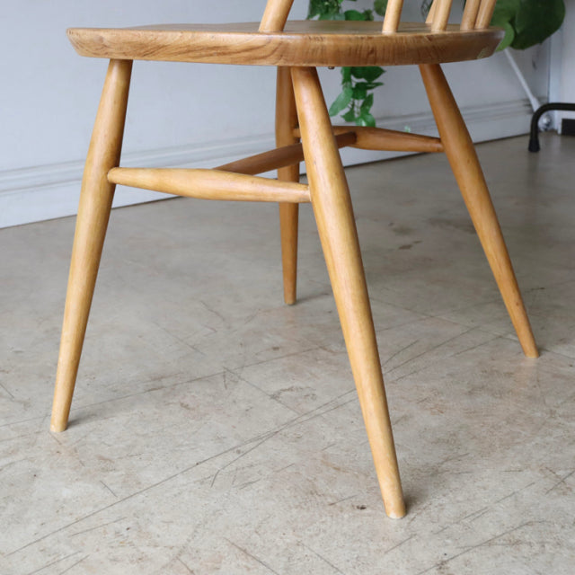 Mid-century British Ercol Quaker chair in natural teak with visible wood grain and tapered legs.