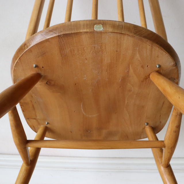 Underside view of vintage British mid-century Ercol Quaker chair in natural teak with visible wood grain and sturdy spindle.
