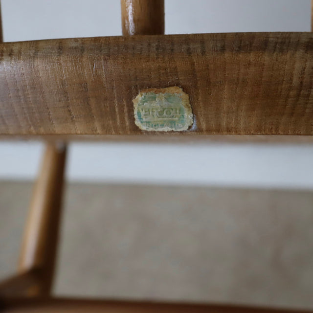 Close-up of vintage British Ercol Quaker Chair natural teak wood with visible wood grain and original metal label under seat .