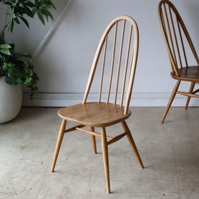 Ercol Quaker dining chair in natural teak with curved spindle back, tapered legs, and mid-century British vintage design.