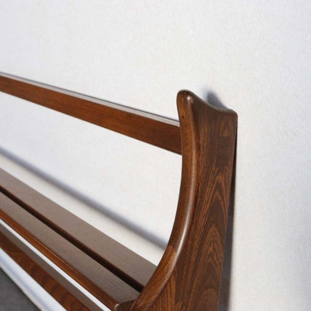 Mid-century British Ercol teak plate rack with smooth curved side panel and rich wood grain finish against white wall.