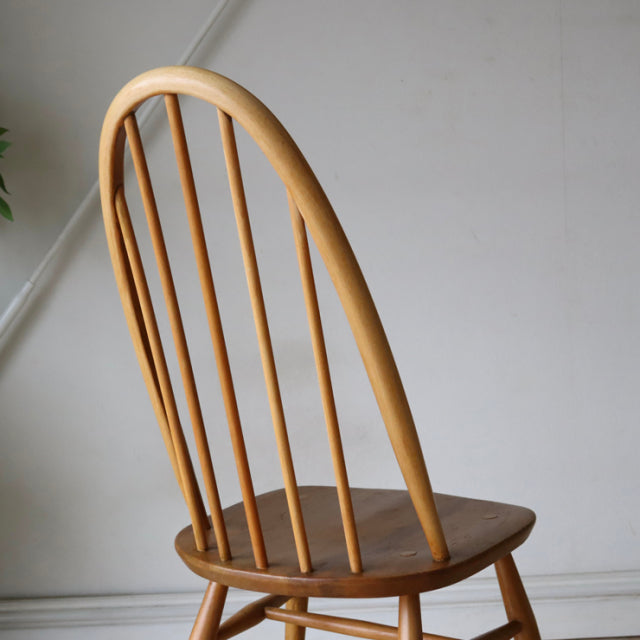 Vintage British Ercol Quaker chair in natural teak with curved spindle back and rounded edges, mid-century Danish influence.