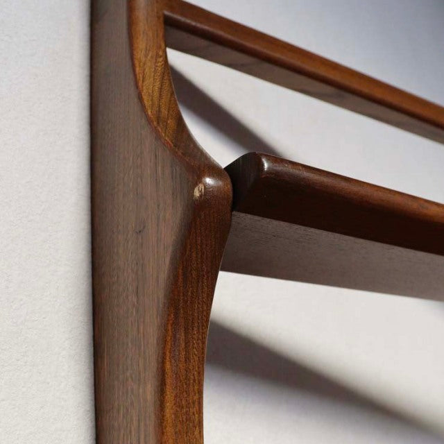 Close-up of vintage British mid-century Ercol teak plate rack corner with smooth curved wood grain and warm finish.