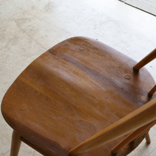 Vintage mid-century British Ercol Quaker chair in natural teak with smooth wood grain and slender legs.