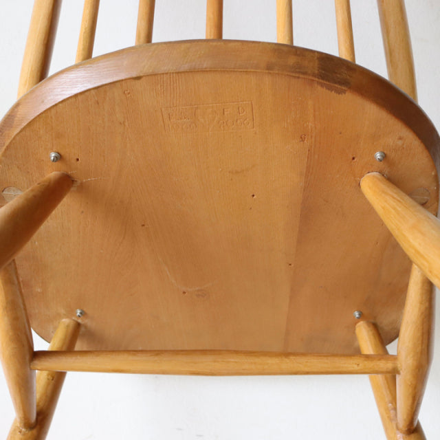 Underside view of vintage British Ercol Quaker chair showing natural teak wood grain, rounded wooden seat, and sturdy.