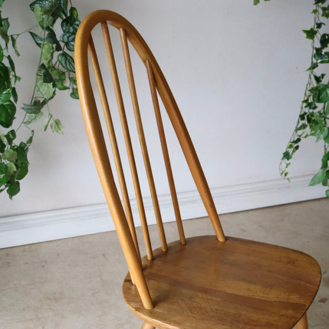 Vintage Ercol Quaker chair in natural teak with British mid-century design, curved spindle back and smooth wood grain.