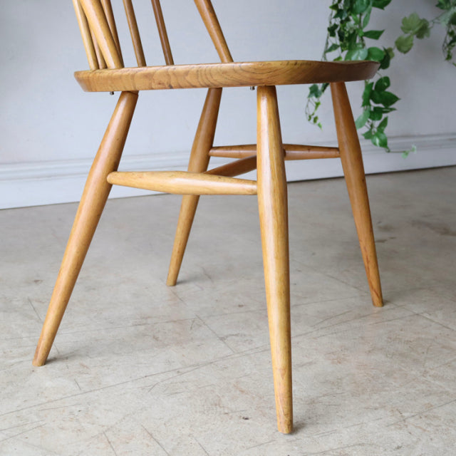 Vintage British Ercol Quaker dining chair in natural teak with spindle back, angled legs, and smooth wood grain from.
