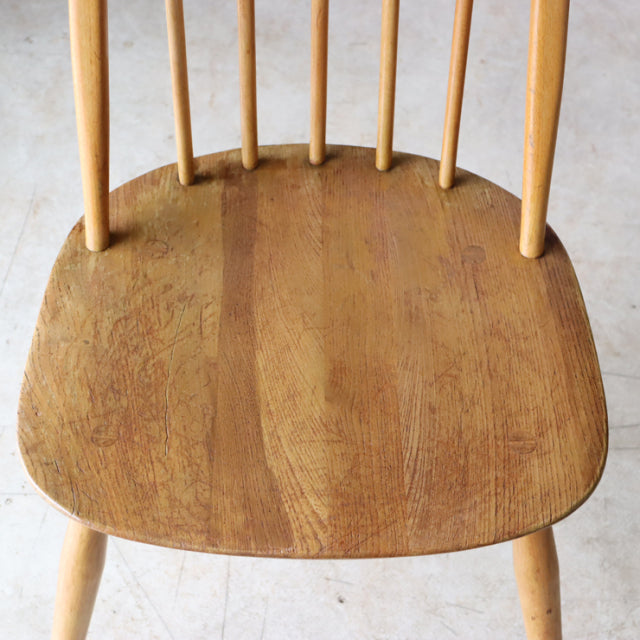 Vintage mid-century British Ercol Quaker chair in natural teak with smooth curved seat and slender spindle backrest.