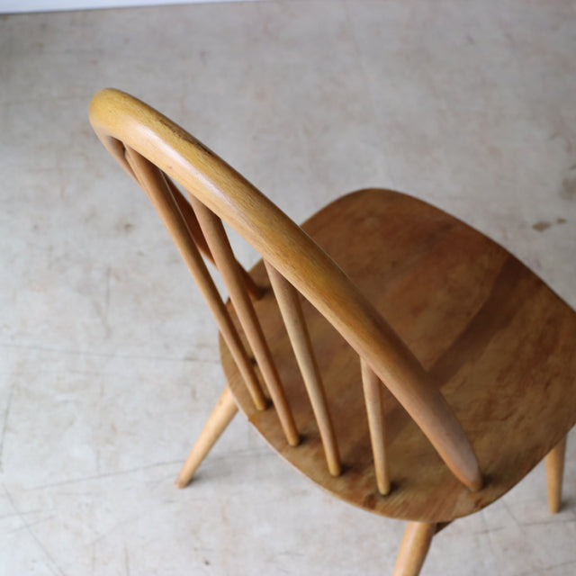Vintage British Ercol Quaker dining chair in natural teak with smooth curved backrest and slender spindle legs in.