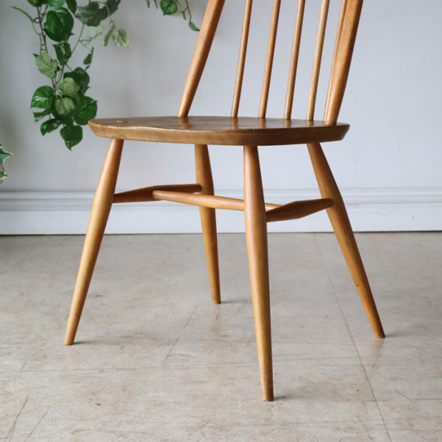 Vintage mid-century ERCOL Quaker chair in natural teak with slender spindle backrest and tapered legs showing smooth wood.