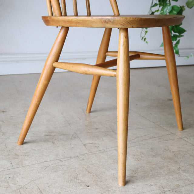 Mid-century British Ercol Quaker chair in natural teak with smooth wood grain and tapered legs.
