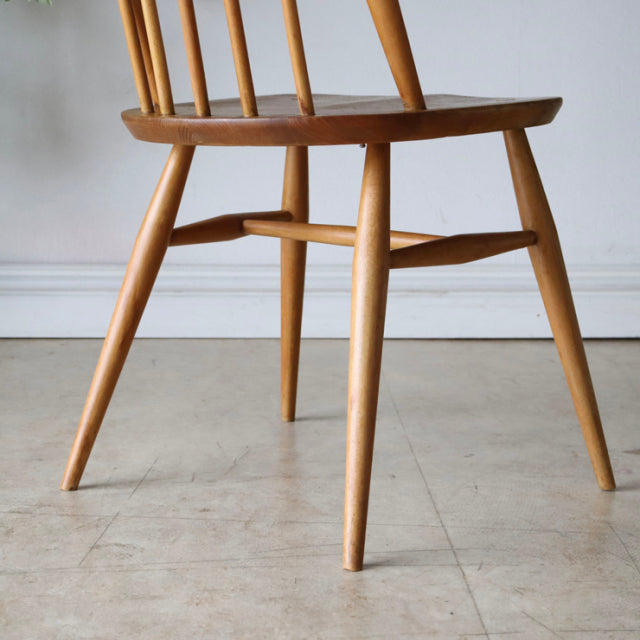 Vintage British mid-century Ercol Quaker chair in natural teak with slender angled legs and smooth wood grain.