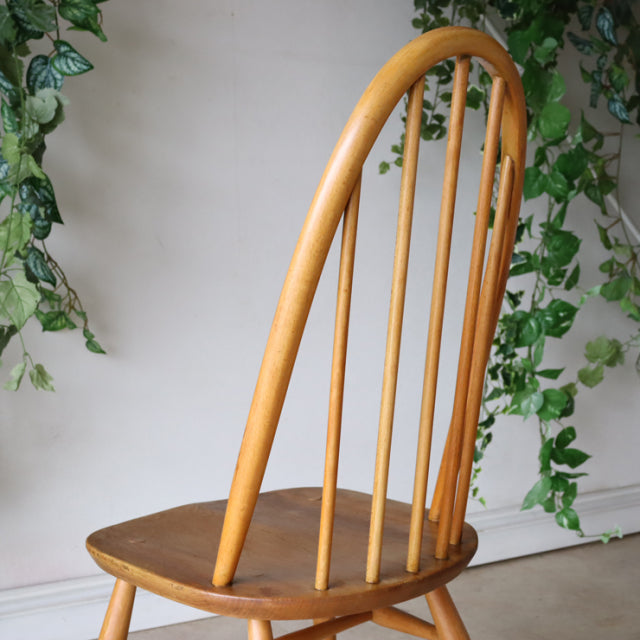 Vintage mid-century British Ercol Quaker chair in natural teak with curved spindle back and smooth wood grain.
