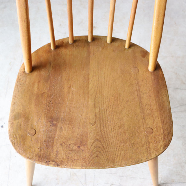 Vintage teak Arcol Quaker dining chair seat showing smooth wood grain and rounded edges with slender spindle legs in natural .