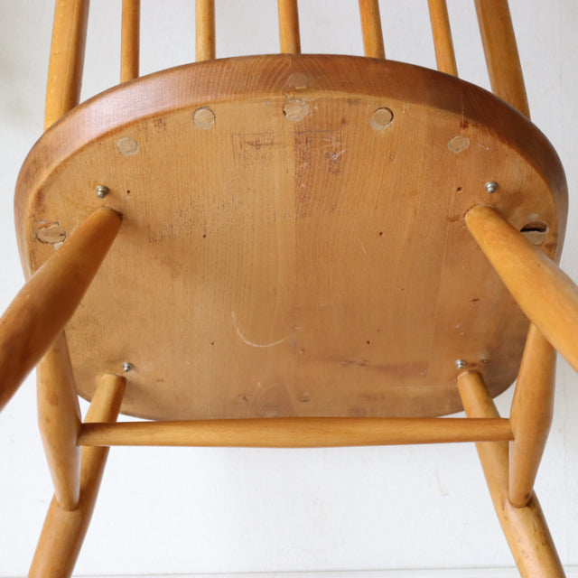 Vintage British Ercol Quaker chair in natural teak, showcasing smooth wood grain, rounded seat edge, and slender mid-century .