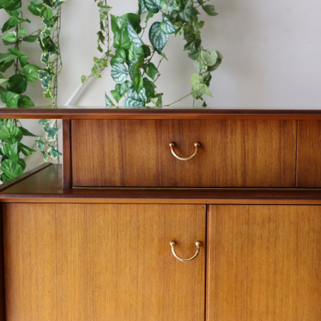 Vintage G-plan teak sideboard with rich wood grain, brass handles, and rounded mid-century British design, showcasing clean.