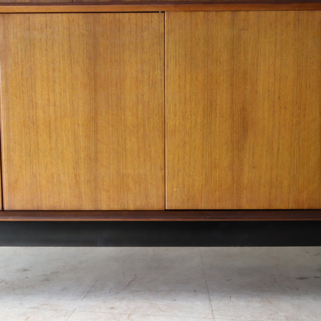 Vintage teak G-Plan sideboard with smooth wood grain, mid-century British design, and sleek black base legs from Denmark.