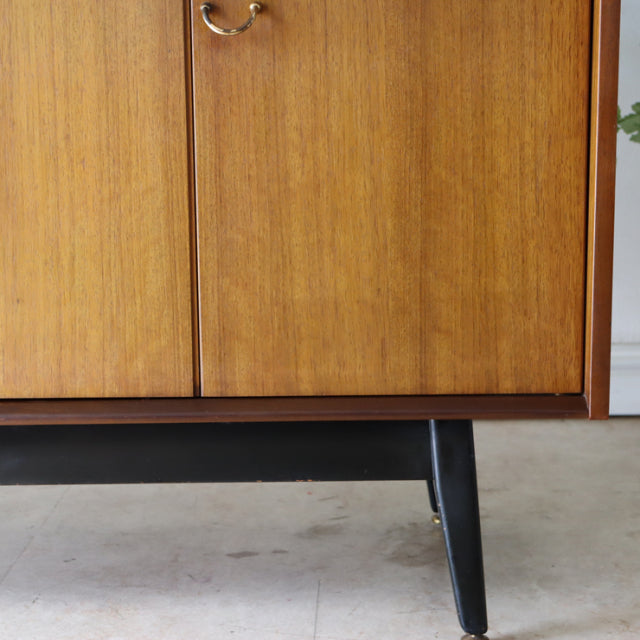 Vintage G-Plan teak sideboard with rich wood grain, mid-century British design, tapered black legs.