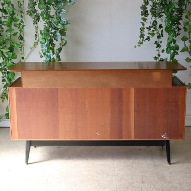 Vintage G-Plan teak sideboard with rich wood grain, slim black tapered legs, mid-century British-Denmark design.