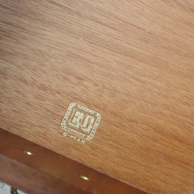 Close-up of vintage G-Plan teak wood grain with British mid-century Denmark style logo stamp on sideboard surface.