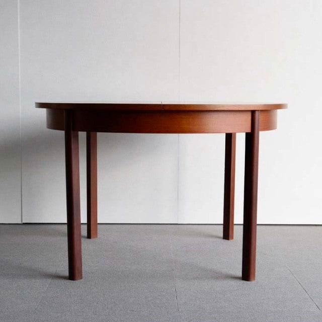 Mid-century vintage teak dining table with smooth oval top and tapered round legs, British and Danish design influence.