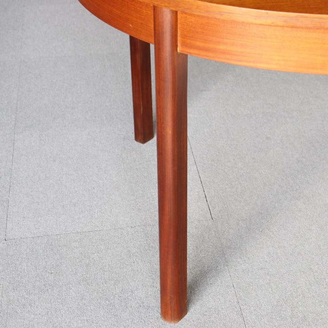 Mid-century British teak dining table leg with smooth wood grain and rounded edges.