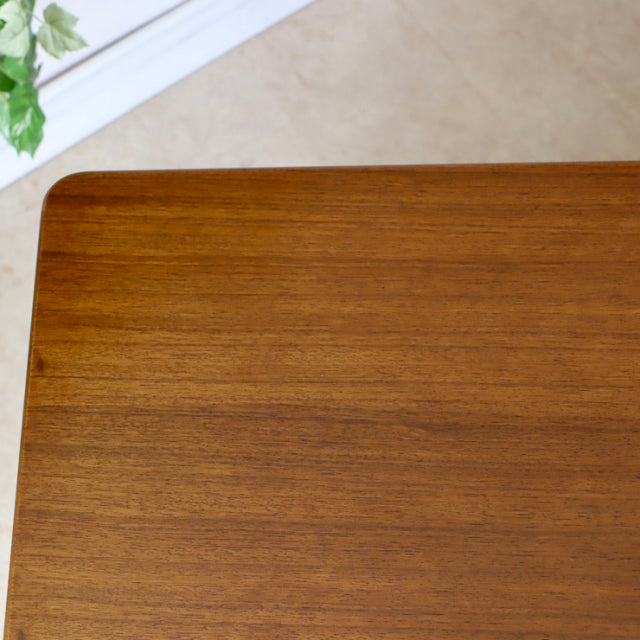 Close-up of vintage British G-plan mid-century teak sideboard top showing warm wood grain and smooth finish with softly.