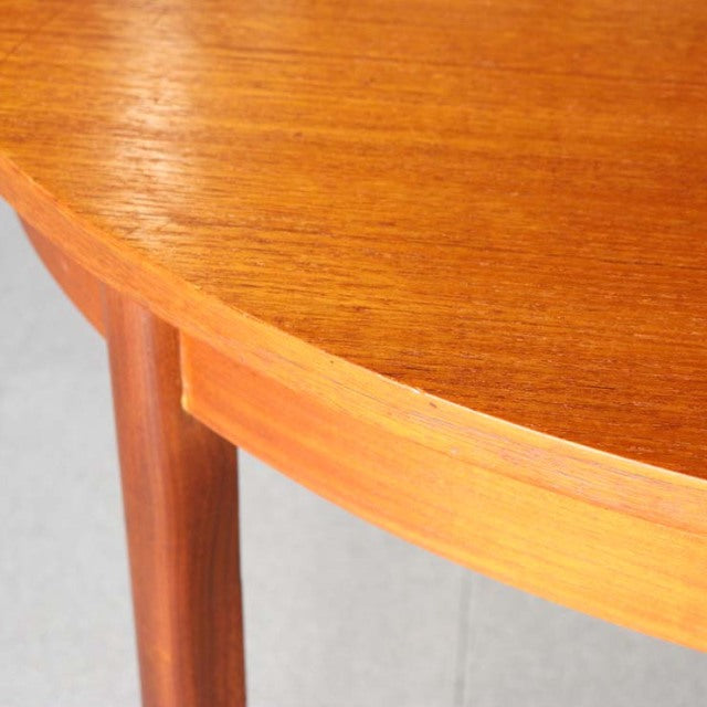 Close-up of vintage British mid-century teak dining table corner showing smooth wood grain and rounded edge with sturdy.