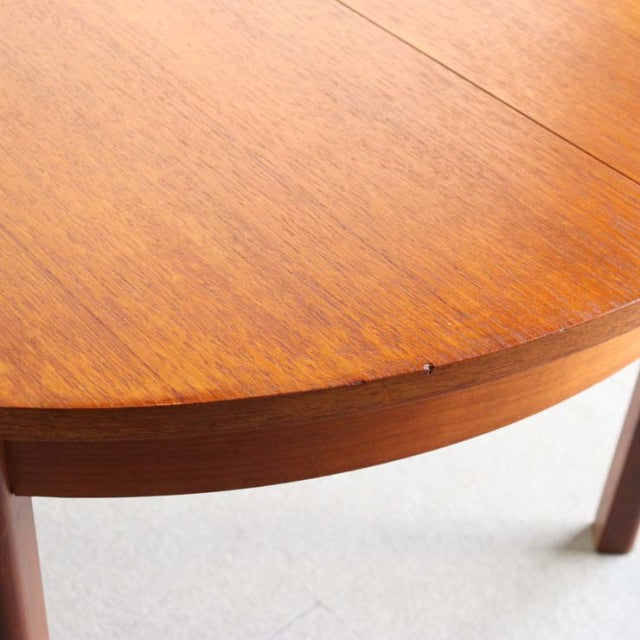 Mid-century vintage British teak dining table with smooth wood grain and tapered legs, polished finish.