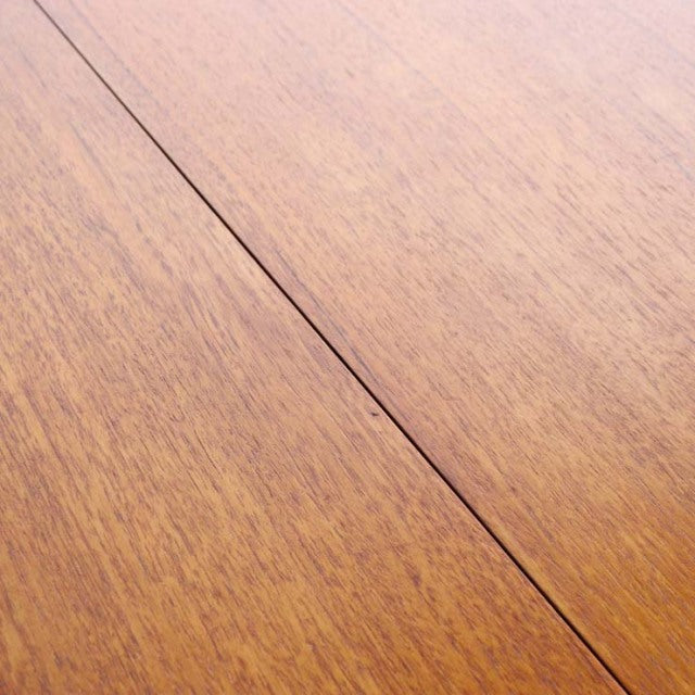 Close-up of vintage British mid-century teak dining table surface showing rich wood grain and smooth finish with visible.