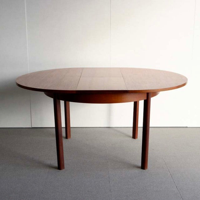 Mid-century British vintage teak dining table with oval top, smooth wood grain, and slender straight legs.