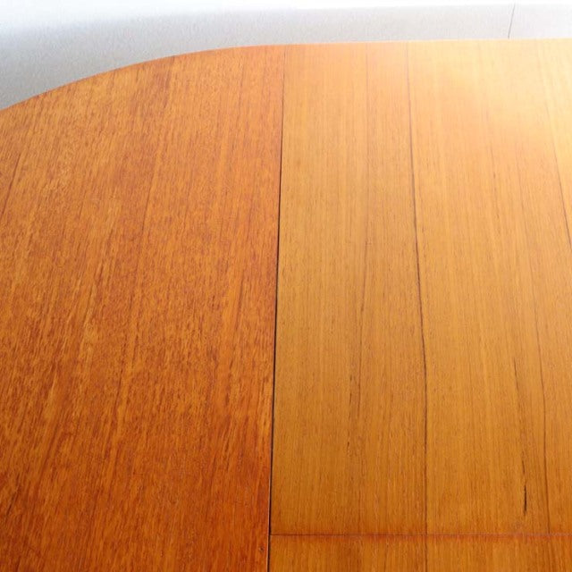 Vintage mid-century British teak dining table with warm wood grain and oval edge detail.