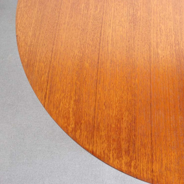 Mid-century British vintage teak dining table with smooth oval top and rich wood grain detail.