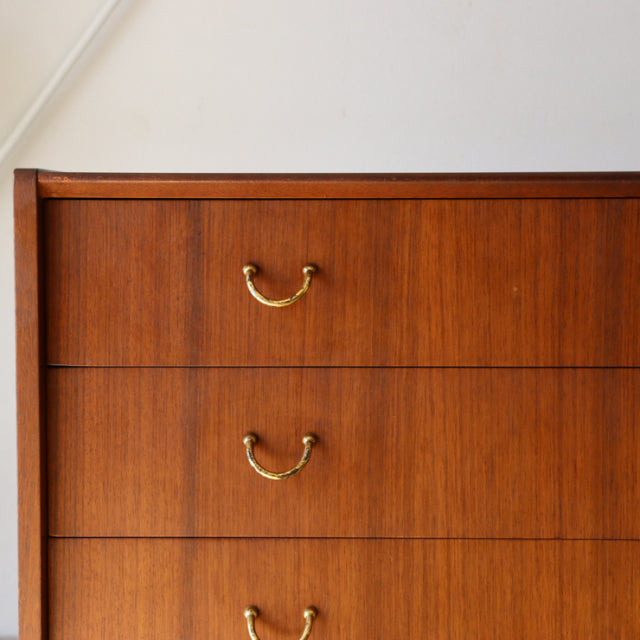 Mid-century British G-Plan vintage teak 4-drawer chest with brass handles and clean wood grain finish.