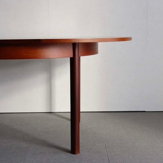 Mid-century vintage British teak dining table with rich wood grain and tapered round legs.