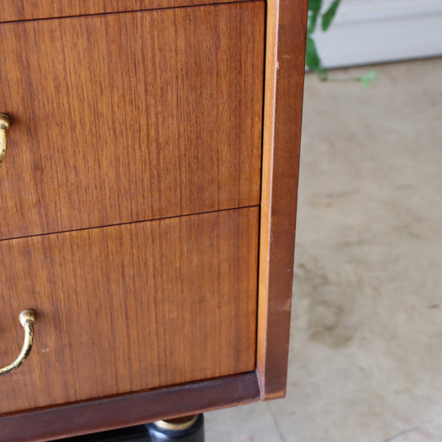 Vintage British mid-century G-Plan teak chest with rich wood grain, brass handles, and tapered legs.