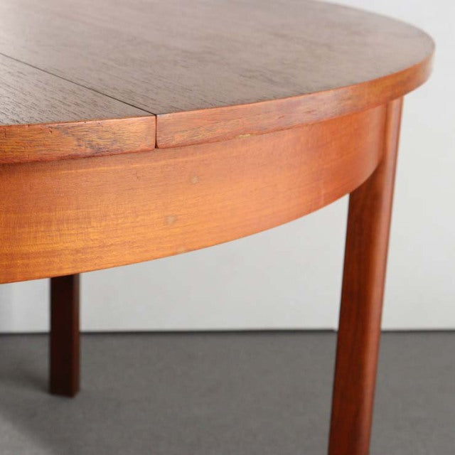 Mid-century vintage British teak dining table with rounded edge and tapered round legs.